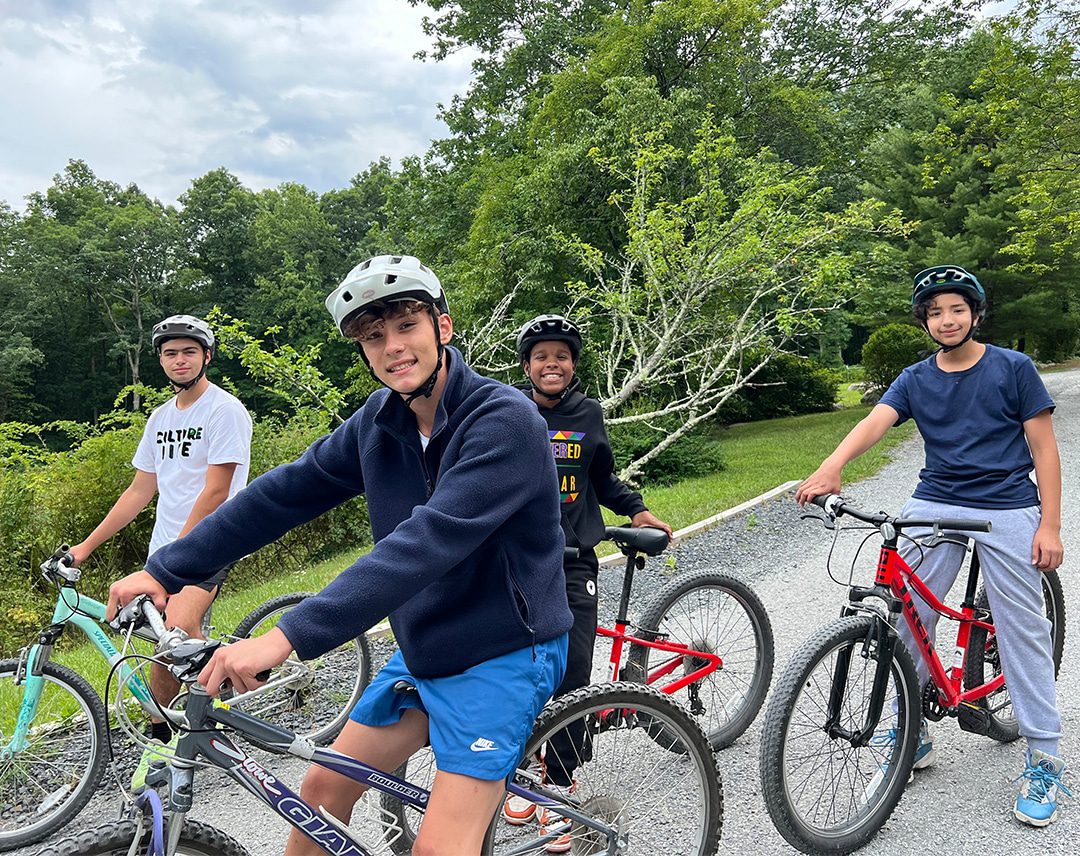 Four teens wearing helmets on bicycles