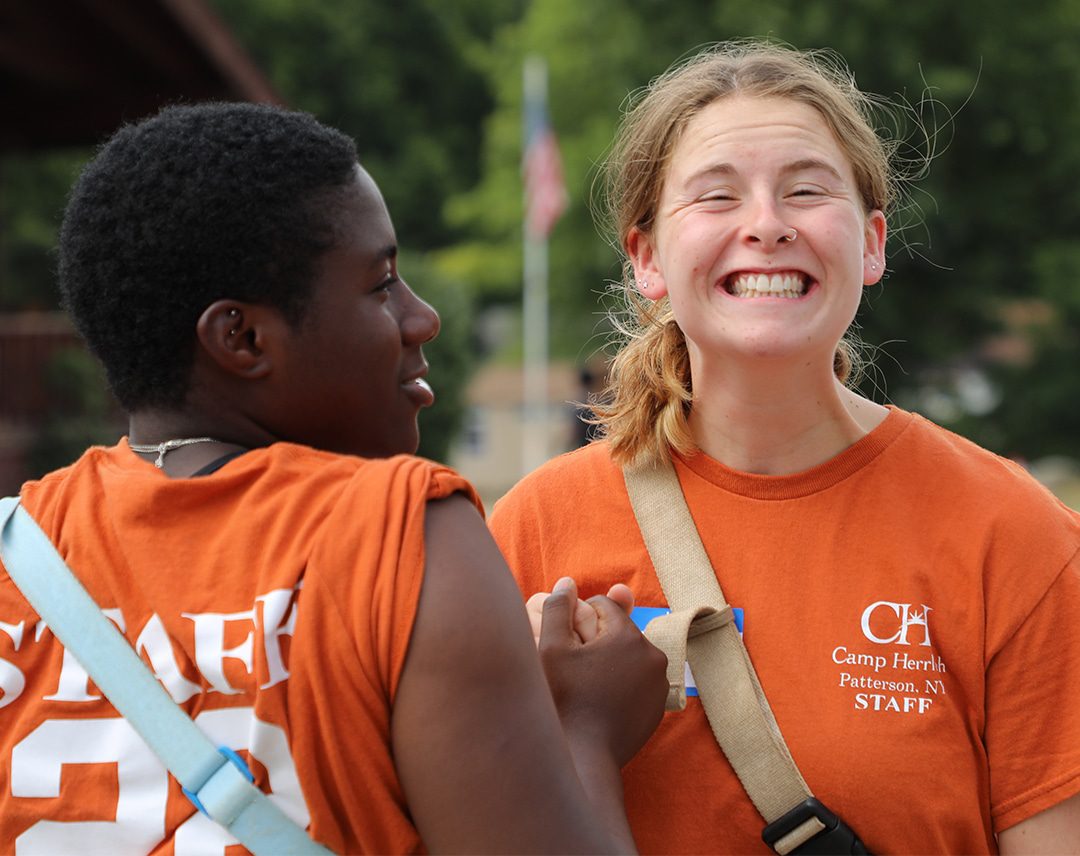 Two camp counselors in orange shirts smiling