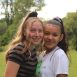 Two smiling teenage girls posing outdoors