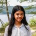 Smiling girl standing by lake in hoodie
