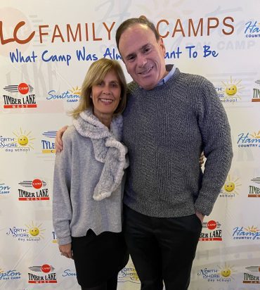 Smiling couple posing at family camp backdrop