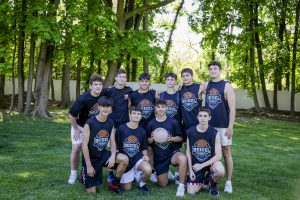 Teen boys basketball team posing outdoors with ball