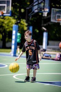 Young boy dribbling basketball on outdoor court