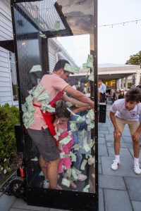 People inside cash-grab booth with flying cash