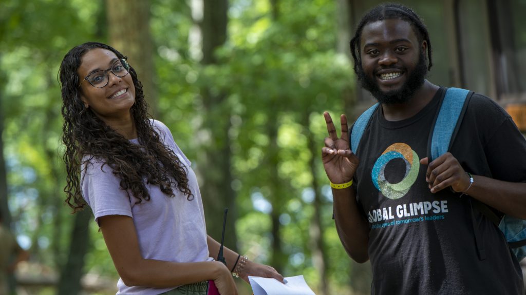 Two smiling people outdoors, man flashing peace sign