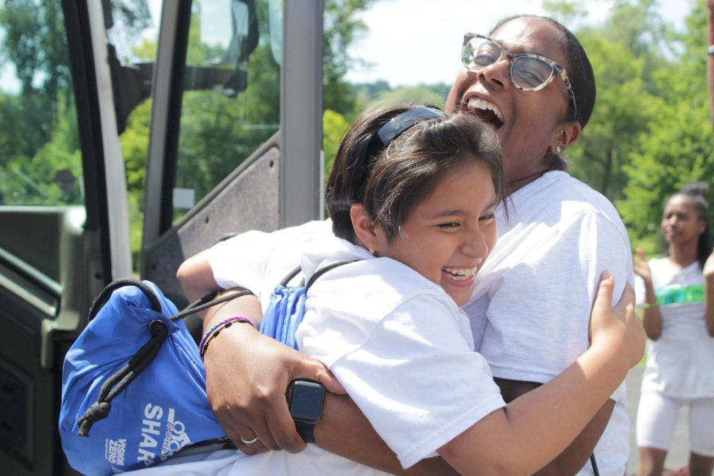 Two people hugging happily near a bus