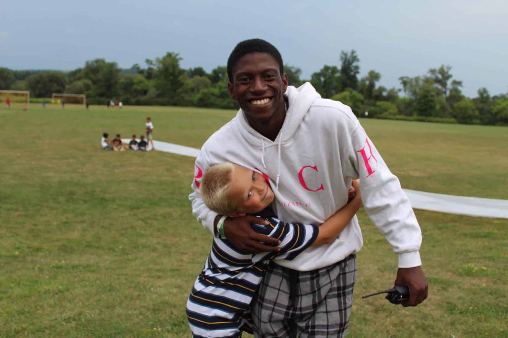 Smiling man hugging young boy on grassy field