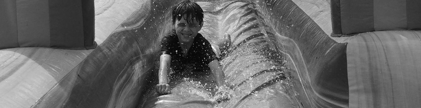 Child sliding down inflatable water slide, splashing