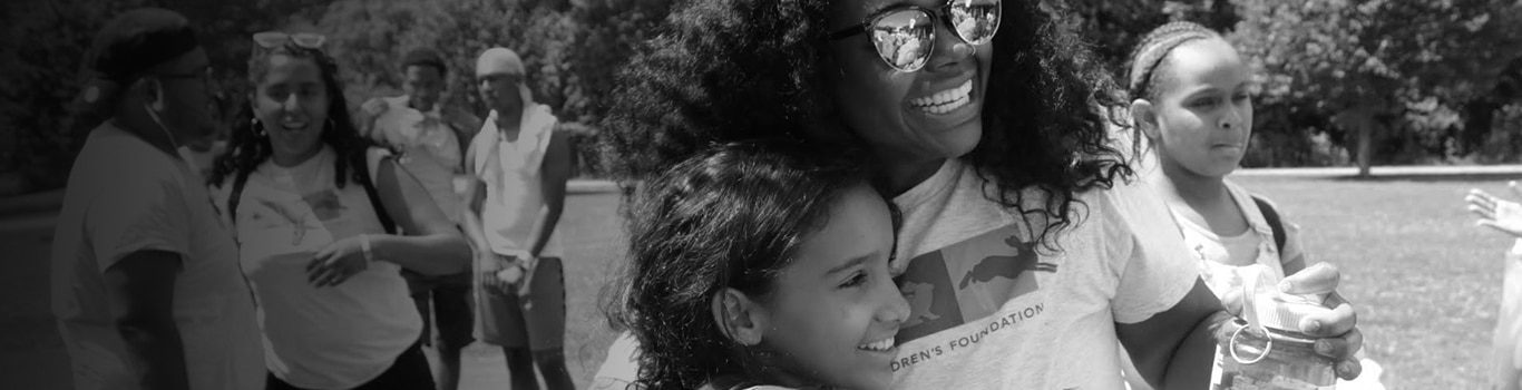 Smiling volunteers hugging outdoors at community event