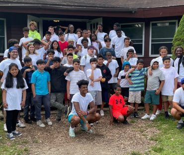 Large group of campers posing outside cabin