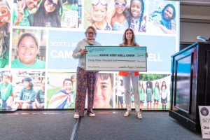 Two women holding oversized camp donation check