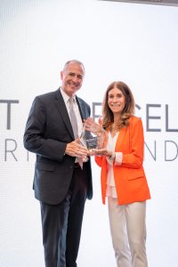 Man and woman smiling, holding award onstage