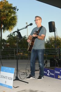 Man playing acoustic guitar on outdoor stage