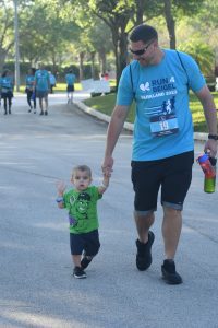 Man holding child's hand during charity run