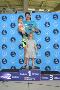Man with two children on first-place podium