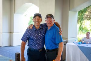 Two smiling golfers hugging at event