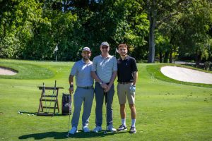 Three smiling golfers posing on sunny golf course