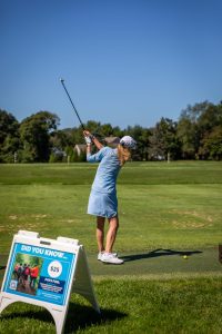 Woman golfer mid-swing on driving range