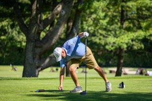Golfer placing ball on tee, driver in hand