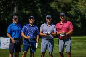 Four golfers standing on green with clubs