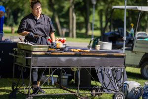 Person grilling burgers at outdoor event
