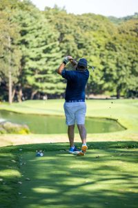 Golfer swinging club on lush golf course