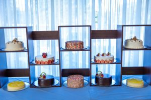 Assorted decorated cakes displayed on wooden shelves