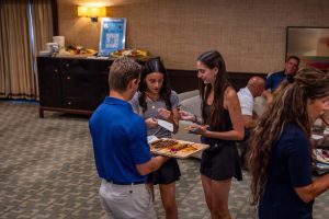Three people tasting skewers at indoor event