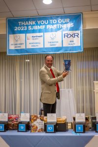 Man holding award under sponsor banner