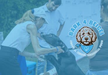 Woman petting black dog at Bark 4 Beigel